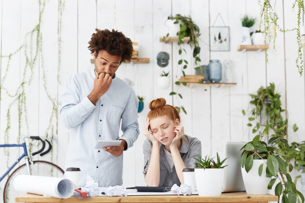 Multiethnic team of young architects feeling stressed out and frustrated, highlighting the importance of effective payroll management.