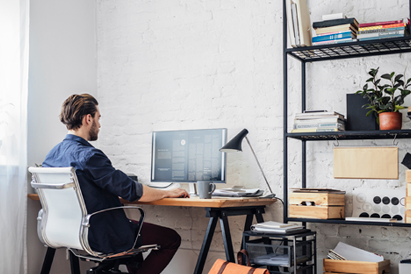 Man working remotely on a computer, representing the impact of remote work on workers' compensation insurance.