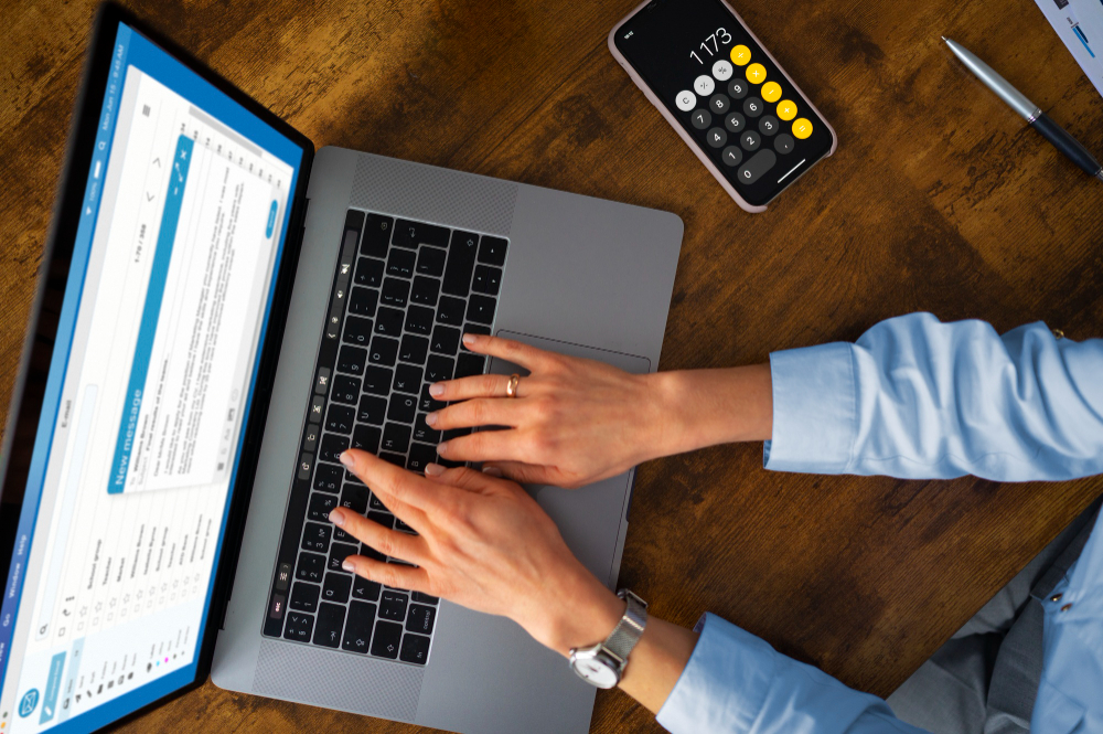 Top view of a woman typing on a laptop, related to payroll management solutions.